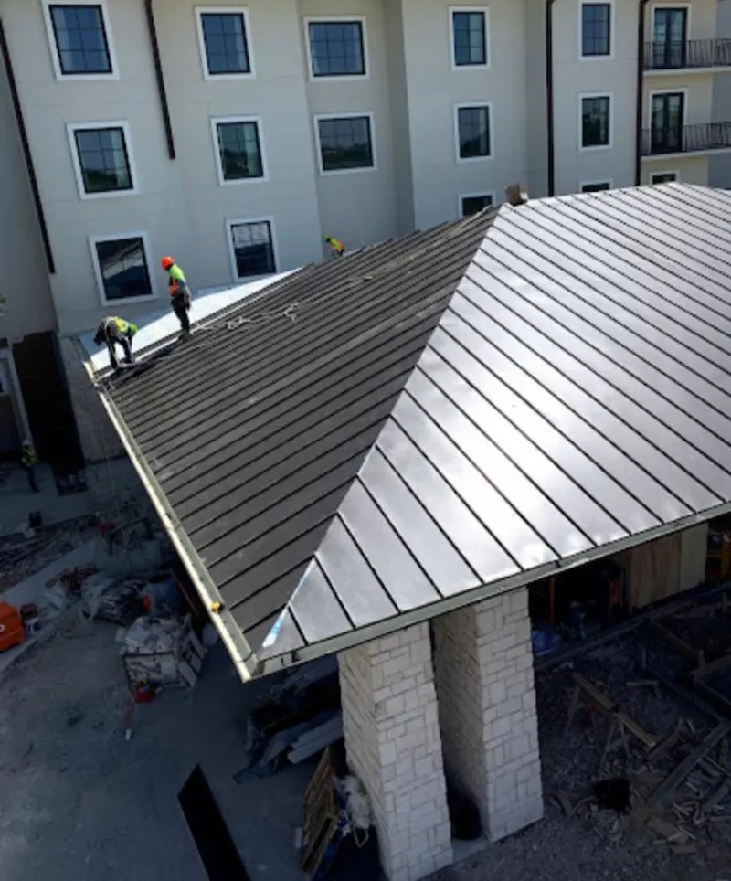Crew installing standing seam metal roof panels on a commercial project in Fox Lake